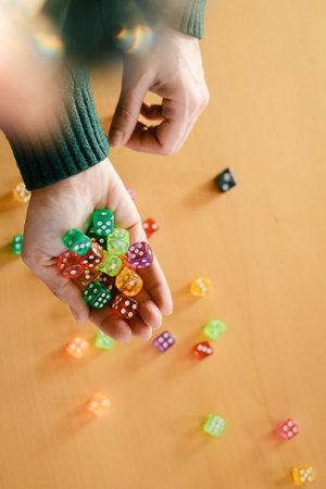 Dice in hands. Table games concept. Closeup of colorful playing accessories over yellow table. Copy space. Gather dice in hands, preparing for an exciting leisure timeの写真素材