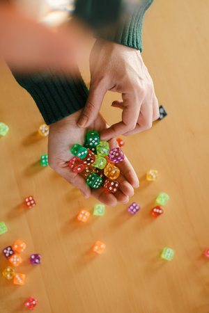 Female Player preparing for session of tabletop game. Dice in woman hands. Table games concept. Copy space. Gather vibrant dice in female hands, exciting leisure time with fortune and chanceの写真素材