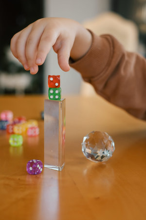 Child hands playing with dice, glass ball and prism, closeup. Tabletop game