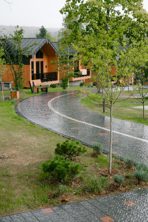 Modern hotel surrounded by nature, relaxation and travel place in the mountains. Lush trees and wet pathway to wooden modern lodging. Morning rain tranquility, nobody around.の写真素材