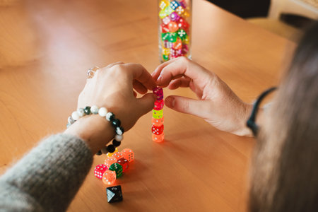 Person stacks colorful dice while playing a table game. Hands with dice , closeup. Trying luck and practicing concentration and calming downの写真素材