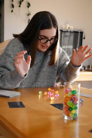 Woman rolling dice on the table with excitement. Gambling and try her luck at table top game. Person scoring and taking riskの写真素材