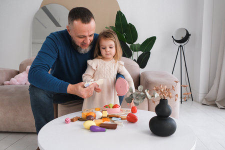 Father lifts his daughter joyfully in bright and airy living room. Large windows, creating a warm and loving atmosphere. Active game and parenting.の写真素材