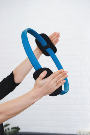 Using flex ring for practicing pilates. Pilates toning exercises for abs with flex ring toner. Hands using pilates circle in a yoga studio. Training and sport activities for adults. Closeupの写真素材