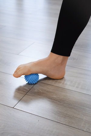 Massaging foot with small ball on the floor. Reflexotherapy and flexibility training. Myofascial relaxationの写真素材