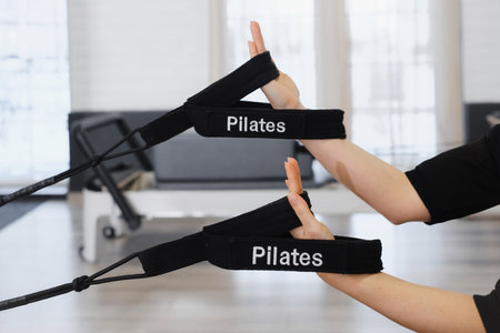 Close-up of hands gripping two rope loops on a pilates reformer. Close up reformer equipment for pilates. Pull body in gym, doing exercises for hands and upper body, improving posture, flexibilityの写真素材
