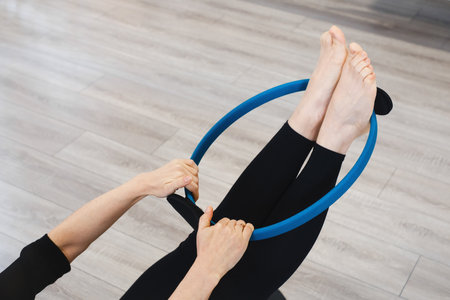 Using flix ring for practicing pilates. Pilates toning exercises for abs with flex ring toner, Hands and legs using pilates circle in a yoga studio. Training and sport activities for adults. Closeupの写真素材