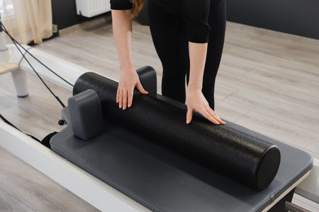Equipment for pilates on reformers. Closeup of hands putting big roll. Empty gym space for training and sport activitiesの写真素材