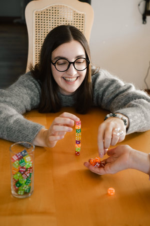 Woman building colorful stack of dice during tabletop game in bright living room. Happy smiley female enjoy playing game at homeの写真素材