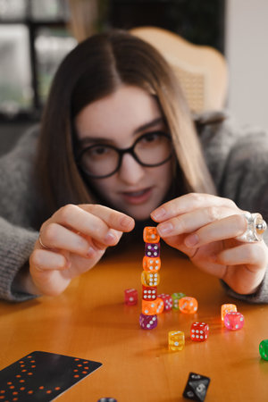 Woman rolling dice on the table with excitement. Trying her luck at table top game. Person scoring and taking riskの写真素材