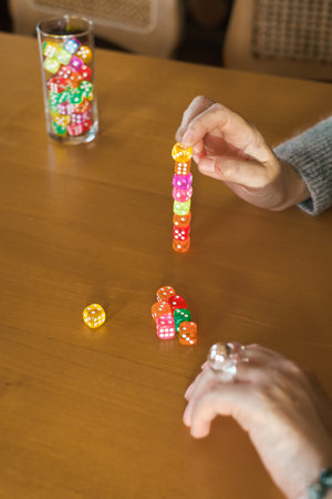 Person stacks colorful dice while playing a table game. Hands with dice , closeup. Trying luck and practicing concentration and calming downの写真素材