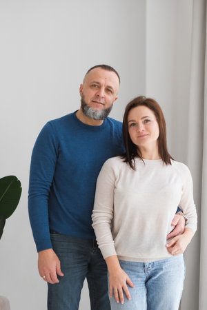 man and woman stand together, embracing each other in a warm home environment. Couple shares moment of affection, representing love and family bonds in their living space. People at their 50s and 40sの写真素材