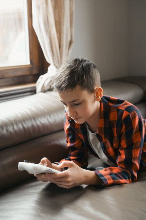 Young Boy Playing Video Game on Couch near Window