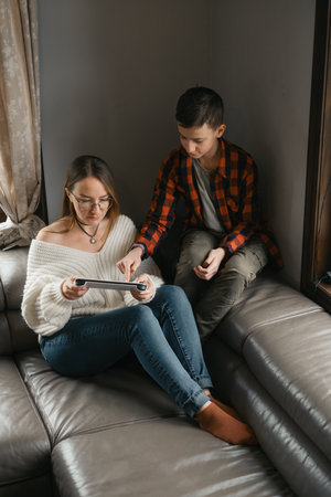 teenage son teaching Mother playing on tabletの写真素材
