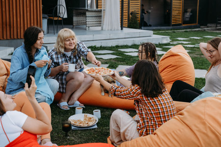 Woman enjoys pizza slice and company outdoors during party