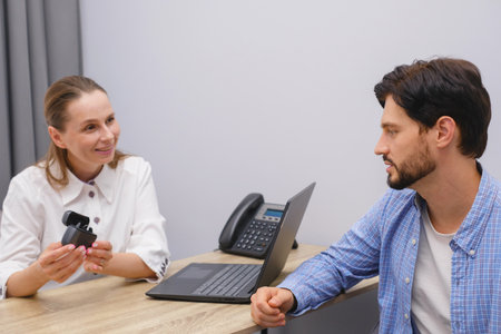 Otolaryngologist showing Modern miniature hearing aids at hospital for manの写真素材