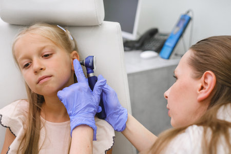 Otorhinolaryngologist examines little girls ear with otoscope, hearing loss indentificationの写真素材