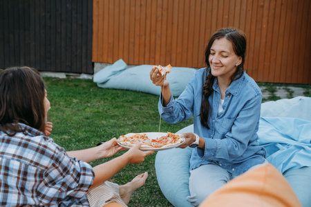 Woman share pizza slice to a friend outdoor