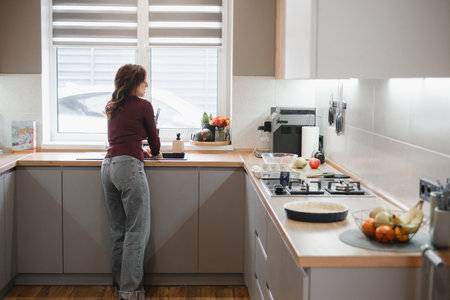 Mom at kitchen window in modern home, food preparation activityの写真素材