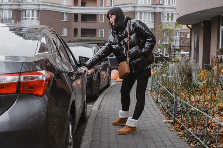 Female owner unlocking vehicle parked on sidewalkの写真素材