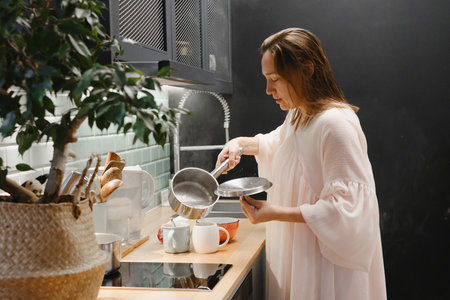 Woman cooking in the morning at modern kitchen with potted plantの写真素材