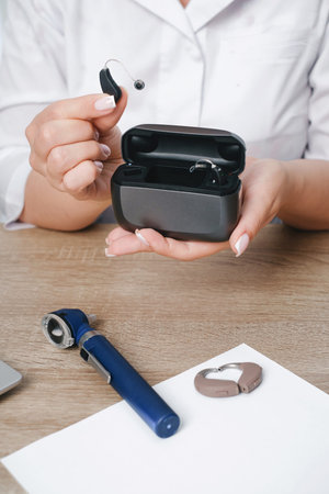 Doctors hands holding an open charging case with two small hearing aids