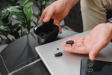 hearing aids on man hand in working environment in office