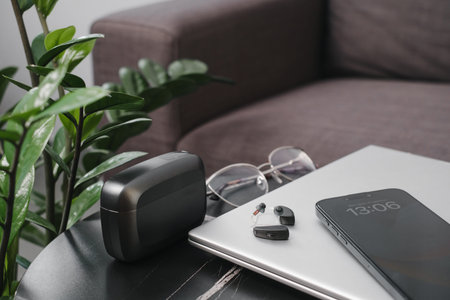 digital hearing aids with charging case and glasses on a black table, business workplace