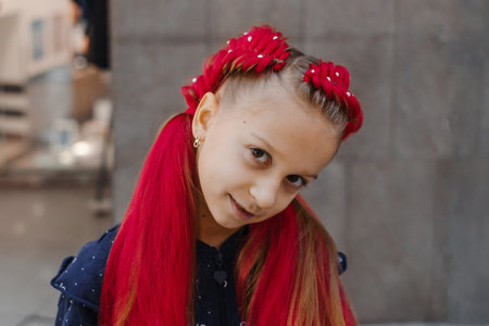 Portrait of smiling girl with red synthetic braids arranged in twin braided buns