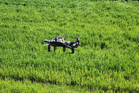 Advanced agricultural drone flying over green field with farm buildings in background, precision...