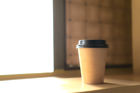 A cup of hot coffee beside the window under warm light of morning sunの写真素材