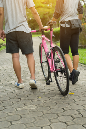 Couple walking with a bike with love and relax in the parkの写真素材