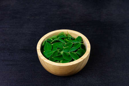 Moringa leaf on wooden bowl on wooden background. Moringa oleifera is both food and herbal medicine.の写真素材