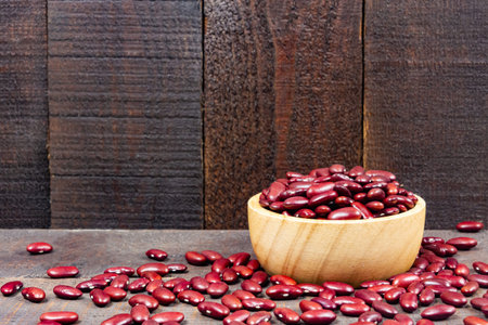 Red kidney beans on wooden bowl on wooden background.