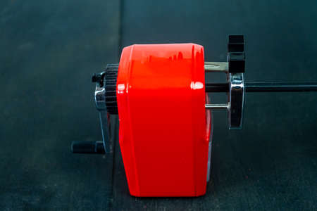 Red pencil sharpener and black pencil on black wooden background.の写真素材