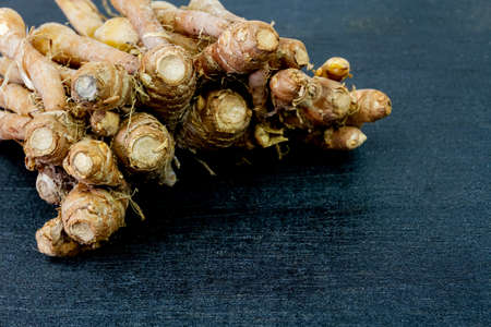 Finger root (Krachai) fresh isolated on black wooden background, finger root is herb and Thai food ingredient.の写真素材
