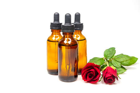 Rose oil in bottle and rose flower isolated on white background. Essential oil product concept.の写真素材
