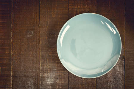 Empty green ceramic plate on wooden background dark tone, copy space.の写真素材