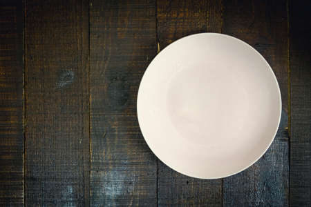 Empty pink ceramic plate on wooden background dark tone, copy space.の写真素材