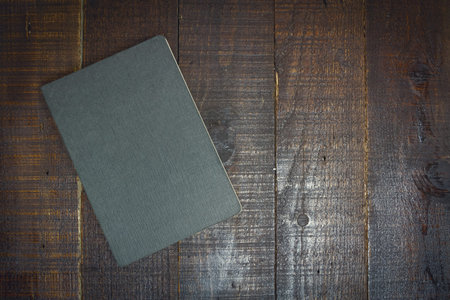 Gray notebook on wooden background dark tone.