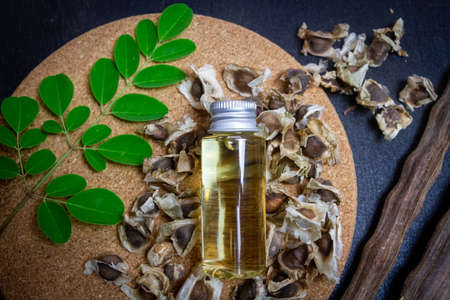 Oil of Moringa in bottle, green leaves, pods and seeds on wooden background. Moringa oleifera tropical herb product concept.の写真素材