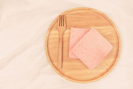 Top view of pink milk flavored sandwich bread on wooden plate and wooden background, warm tone.