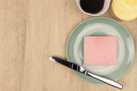 Top view of pink milk flavored sandwich bread on light green ceramic plate and wooden background,...