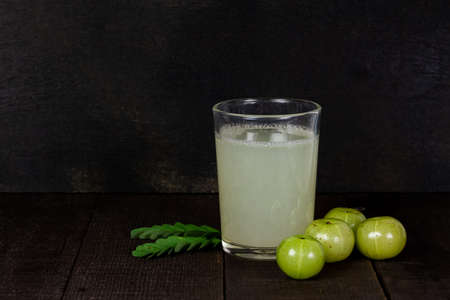 Indian gooseberry fruit and juice or Amla (phyllanthus emblica) on wooden background, dark tone.の写真素材