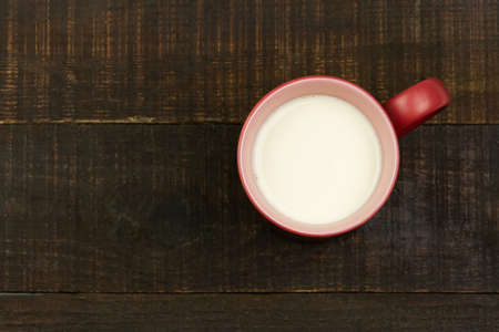 Red cup of milk on wooden background. Top view.の写真素材
