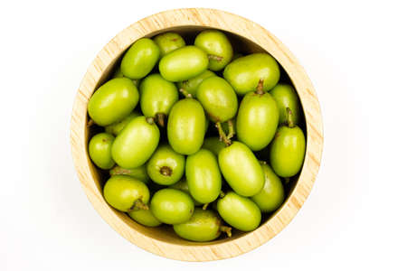 Fresh Neem fruit on wooden bowl isolated on white background, Top view. Neem fruit is an excellent moisturizing and contains various compounds that have insecticidal and medicinal properties.の写真素材