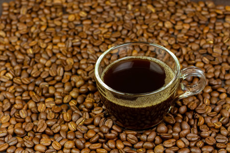Black coffee in transparent glass on coffee bean background.