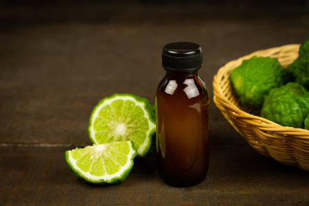 Bergamot oil in bottle and fresh bergamot fruit in wicker basket on wooden background.