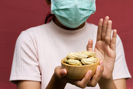Young girl wearing face mask refuses to eat peanuts. Allergy foods concept.の写真素材