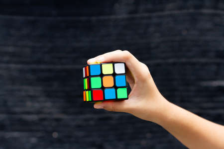 SAMUT-SAKHON, THAILAND - MAY 09, 2021 : Hands of young girl showing the Rubik's Cube puzzle on black background, Illustrative editorial.のeditorial素材